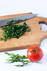 Chopped fresh herbs, a knife, wooden boards, and red tomato