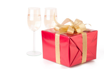 Red gift box with golden bow and champagne, white background