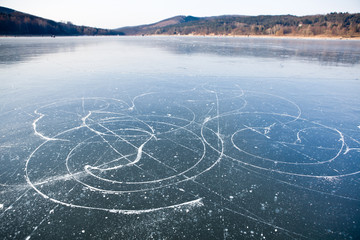 Fototapeta na wymiar Lodowe szlaki łyżwy na zamarznięte jezioro, zapora Brno