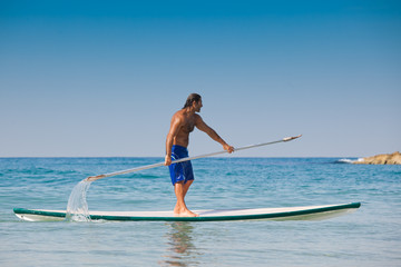 Fototapeta na wymiar The guy with an oar on a surfboard.