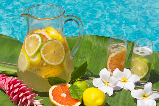 Two glasses and Jug lemonade on edge of swimming pool.