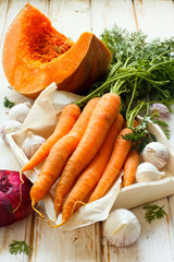 Pumpkin, carrot, garlic and red onion on white wooden background