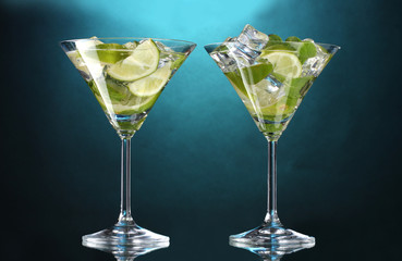 glasses of cocktails with lime and mint on blue background