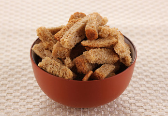 Appetizing rusks in bowl on beige napkin