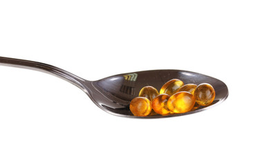 Spoon with pills isolated on white