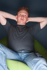Obraz premium Portrait of young man sitting at home and watching tv