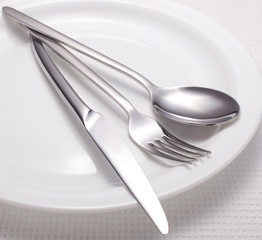 fork, knife, spoon and a white plate