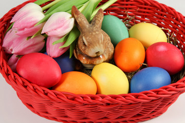 bunte Ostereier, Tulpen und Osterhase im Korb
