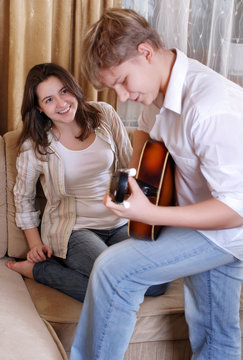 Teenage boy playing on guitar for his girlfriend