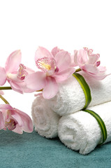 white towels on blue towel with branch orchid in a bowl