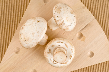 Fototapeta na wymiar A wood cutting board with three white mushrooms