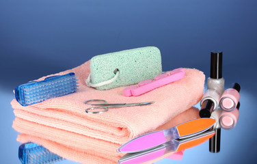 Pedicure set on pink towel on blue background