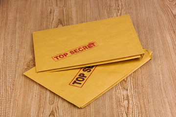 Envelopes with top secret stamp on wooden background