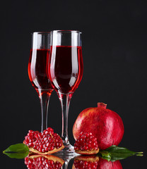 ripe pomergranate and glasses of wine on black background