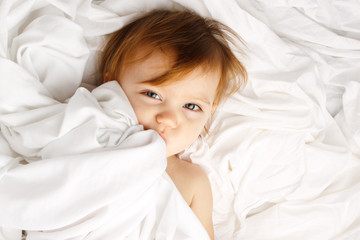 Beautiful child wrapped in white sheets