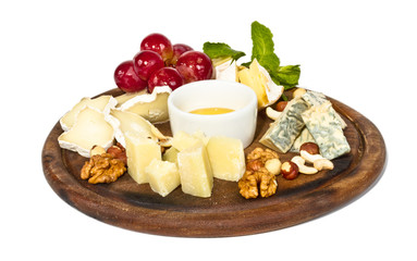 Various types of cheese with honey, nuts and grapes on plate, is