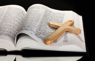 Russian bible and wooden cross on black background