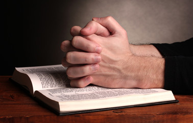 Hands folded in prayer over a Holy bible