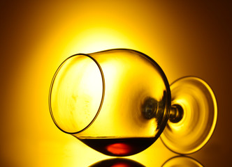 Glass of cognac on yellow background