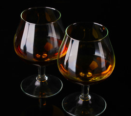 Two glasses of cognac on black background
