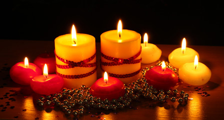 Beautiful candles and decor on wooden table on black background