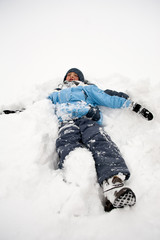 Fototapeta na wymiar Young boy lying on the snow.