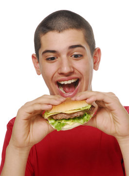 Ni&ntilde;o sujetando y comiendo hamburguesa.