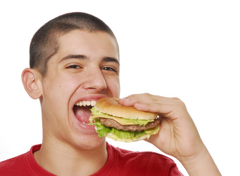 Niño sujetando y comiendo hamburguesa.
