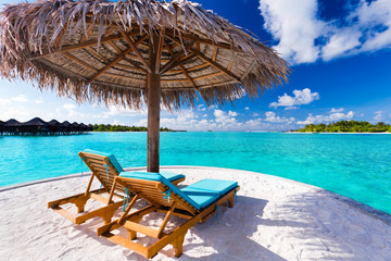 Naklejka na ściany i meble Dwa krzesła i parasol na tropikalnej plaży