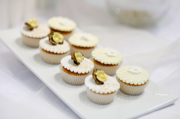 Decorated white vanilla cream cupcakes on a white plate