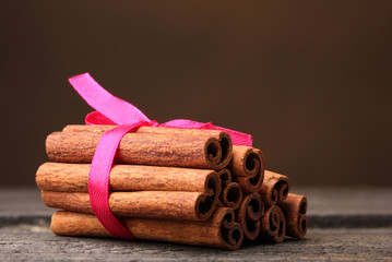 Cinnamon sticks on wooden table on brown background