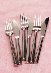 Forks and knives on a pink tablecloth