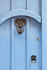 Blue door with black door knocker in wrought iron.