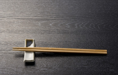 箸と陶器の箸置きと黒木目