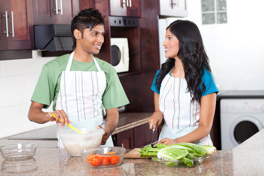 Modern Young Indian Couple Cooking In Kitchen