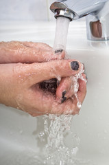Washing hands in bathroom with  hot water