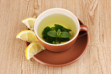 Mint tea with mint leaf and lemon on wooden background