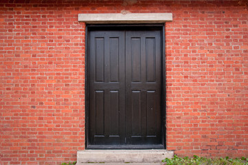 Obraz na płótnie Canvas Czarne drzwi na zewnątrz cegła