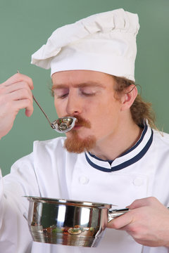 young Chef tasting food with a tablespoon