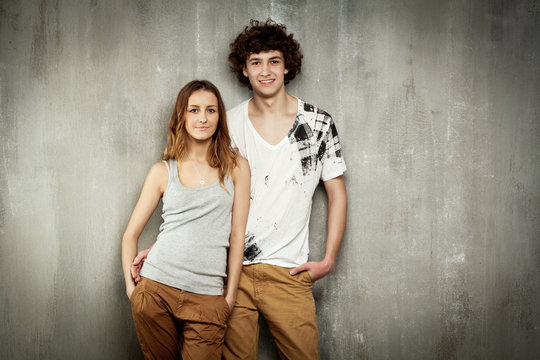 Artistic portrait of a young couple on a gray, textural backgrou