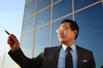 young businessman pointing with pen front office building