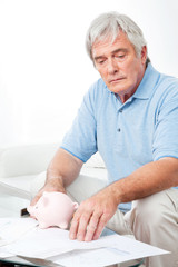 Senior mit Rechnungen und Sparschwein