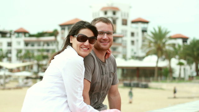Young happy couple sitting by the beach
