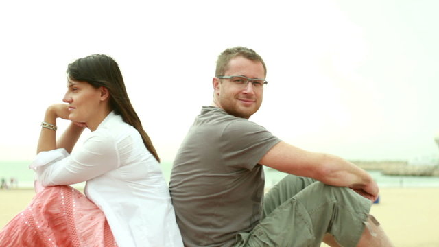 Young happy couple sitting by the beach