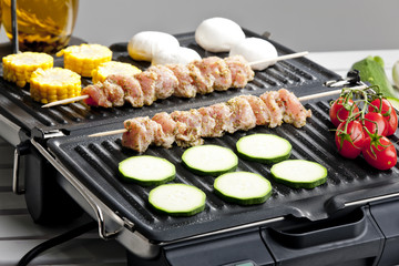meat skewers and vegetables on electric grill