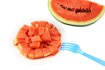 Red watermelon dish and blue fork on white background.