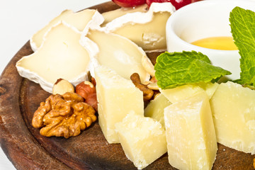 Various types of cheese with honey, nuts and grapes on plate, is
