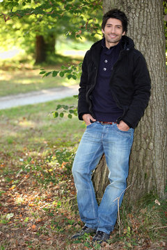 young man near a tree in autumn