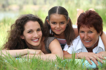 Grandmother, mother and daughter lying in the grass