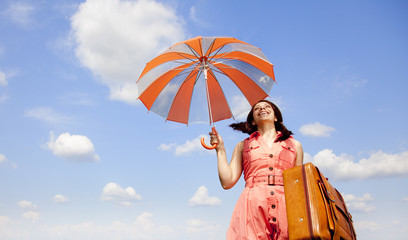 Brunette enchantress with umbrella and suitcase